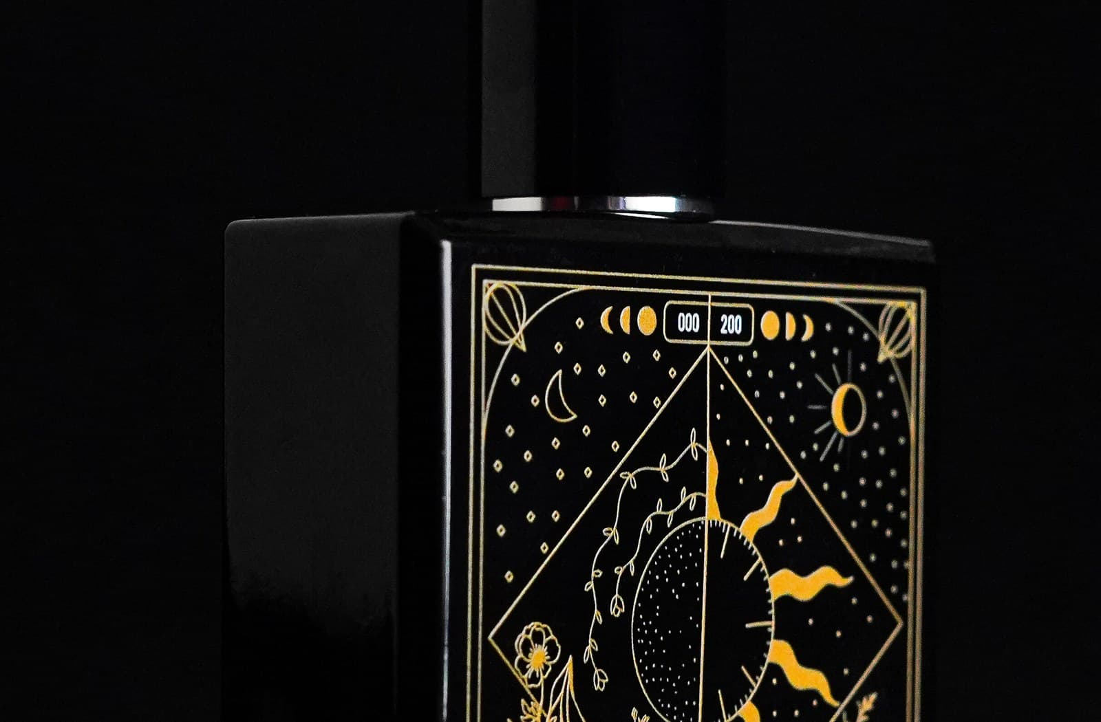 TAKUMI GENSŌ — the bottle's gold celestial face in darkness, moon and sun in one frame with the edition number 000/200 pressed between them