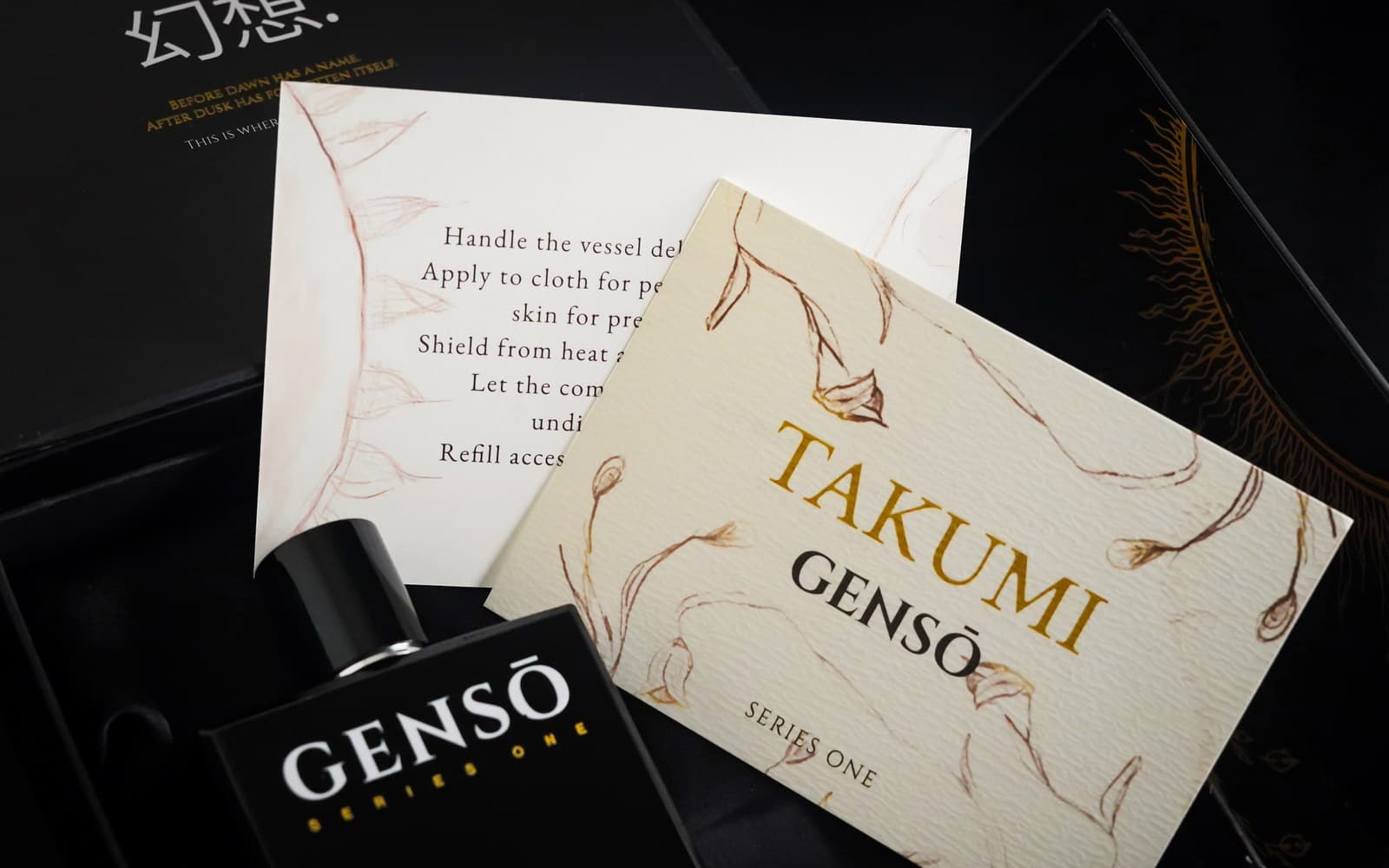 TAKUMI GENSŌ — the full Series One set laid on black: the bottle, the signed numbered cards, the cream TAKUMI card and the stickers, arranged like a flat-lay