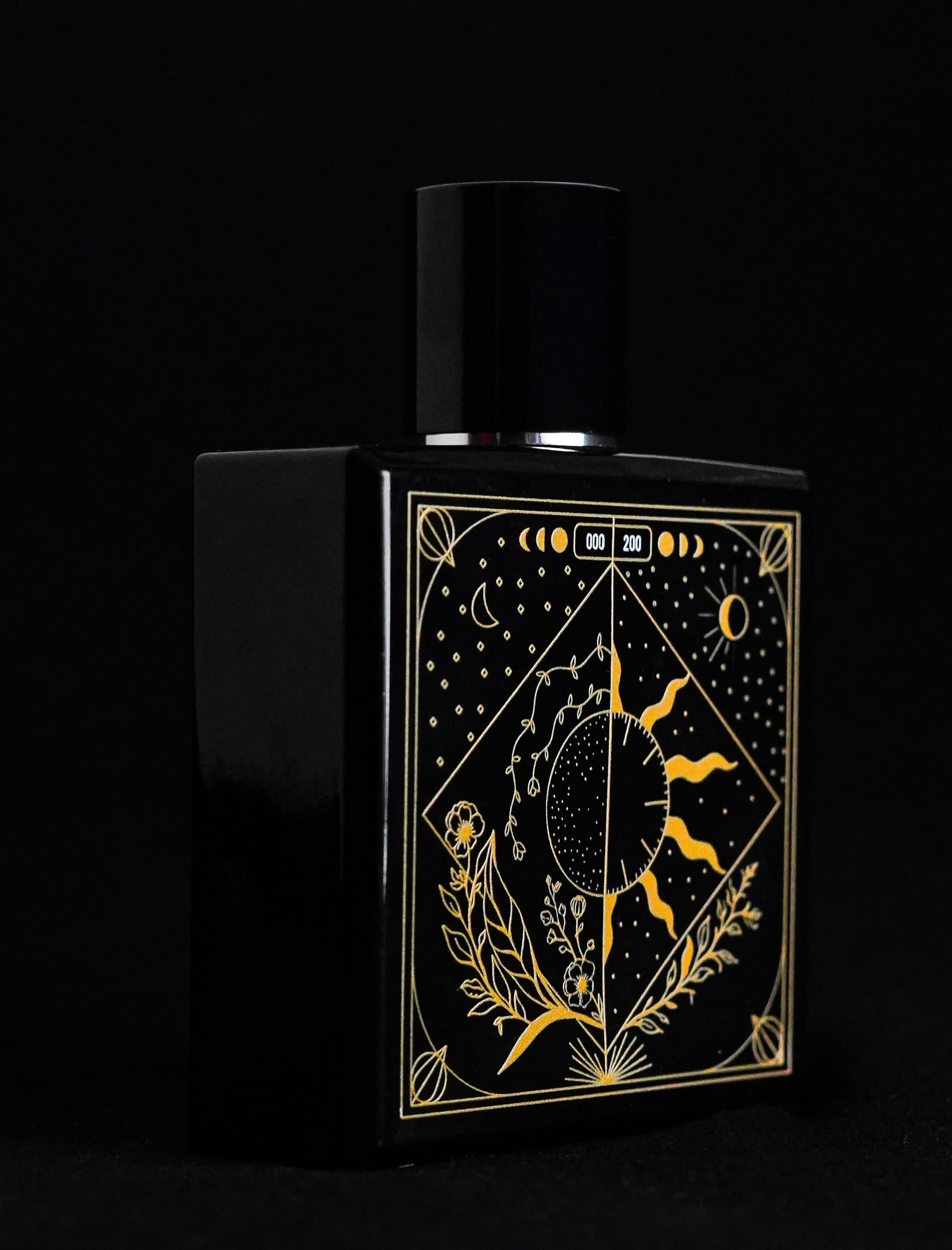 TAKUMI GENSŌ — the bottle's gold celestial face glowing in deep darkness: a crescent moon and sun in one gold-line frame with the edition number 000/200, botanicals below