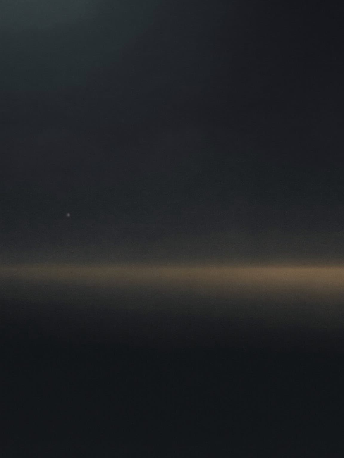 The hour between night and day: a dark sky dissolving into a faint band of gold light on the horizon